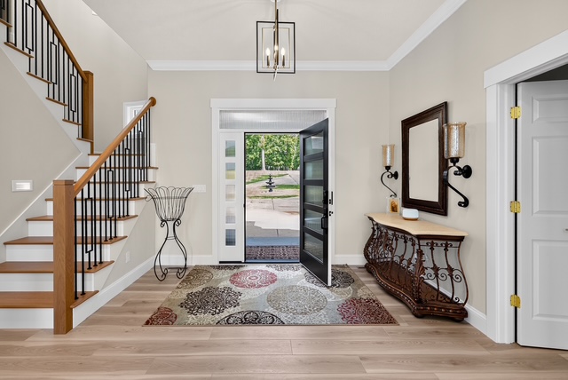 The entry hall with glass front door, chandelier and staircase rising to the upper level