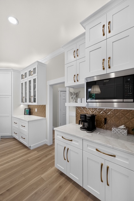 The butler’s pantry and coffee bar with brass hardware, glass-front cabinets and a patterned copper backsplash