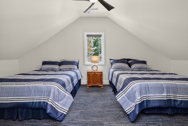 A vaulted upper-level bedroom with two beds set beneath the eaves