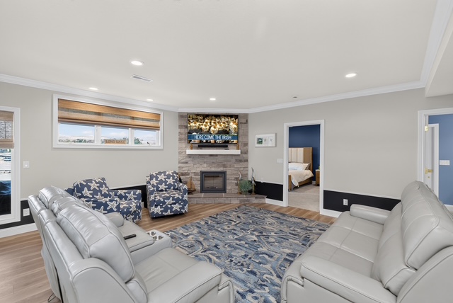 The lower-level lounge with reclining sofas, stone fireplace and a large television for game day