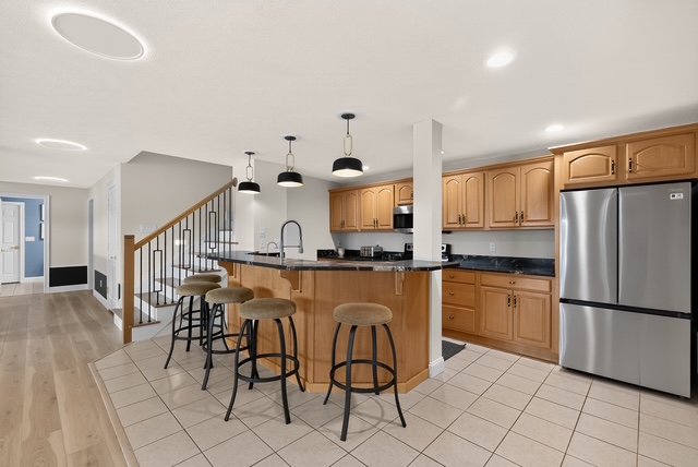The lower-level kitchen and bar with island seating, beside the stair to the main level