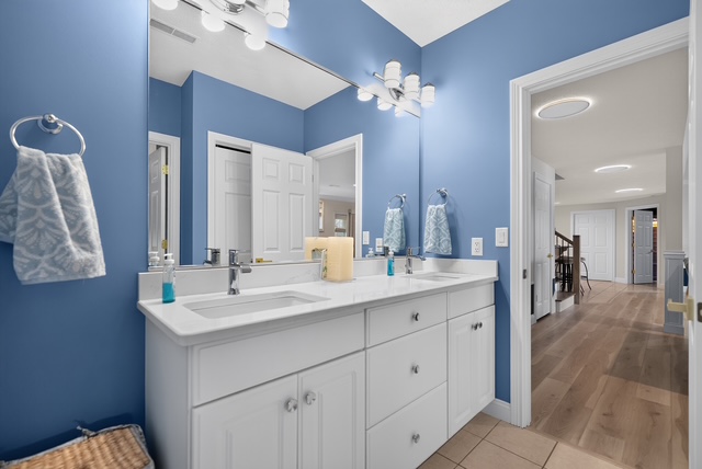 A shared guest bath with a double vanity, wide mirror and hallway access