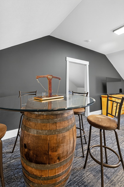 A whiskey-barrel pub table with stools in the vaulted game loft