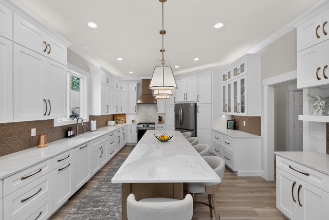 The chef’s kitchen with a marble waterfall island, seating for six and custom white cabinetry