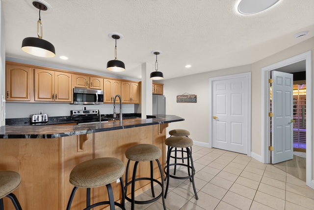 The lower-level bar with granite counter, stool seating and stainless appliances