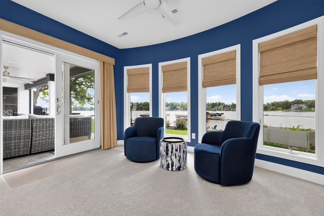 A navy sitting nook with swivel chairs, wraparound lake windows and doors to the screened porch