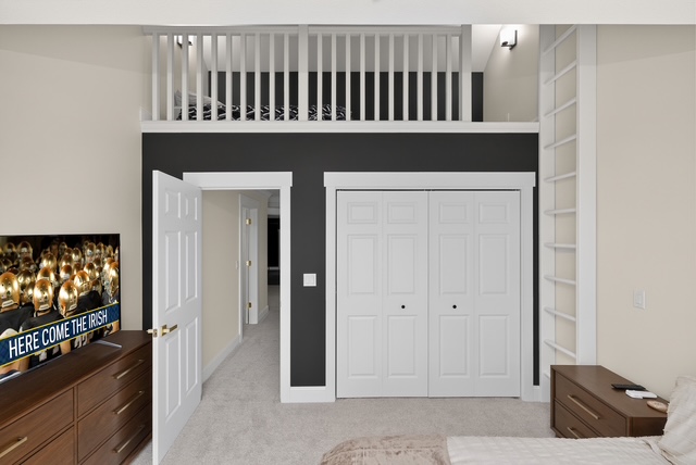 A guest bedroom with an open loft above and built-in shelving