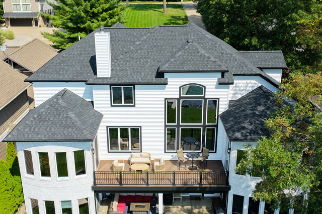 Overhead view of the estate's upper deck lounge and covered lower patio facing the lake