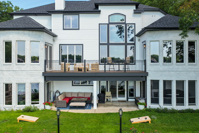 Aerial view of the Lavish Retreat estate's lake-facing elevation, with covered deck, terrace and lawn
