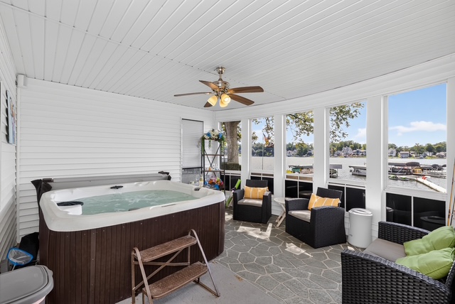 The screened lakefront spa room with Jacuzzi, wicker lounge seating and windows onto the water