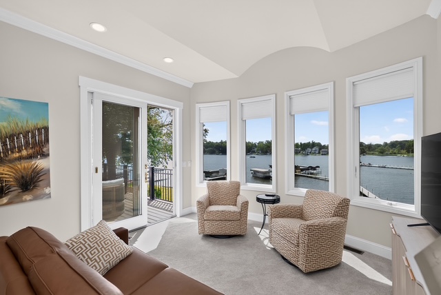 A sitting room with swivel chairs, wraparound windows onto the water and doors to the deck