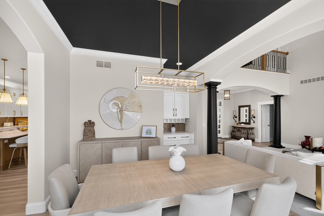 The dining room with black coffered ceiling and archways opening to the kitchen and great room
