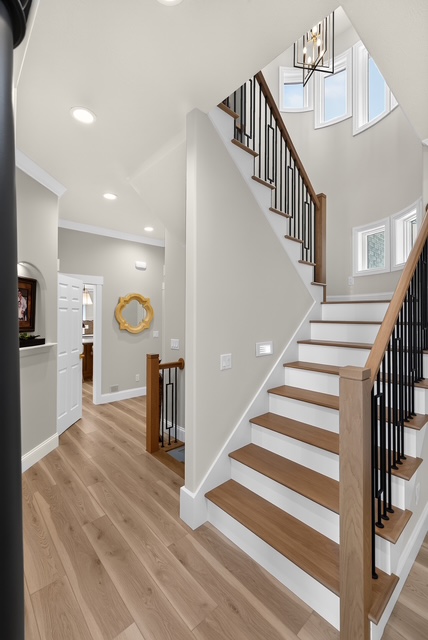 The entry foyer with an open staircase rising beneath a chandelier and clerestory windows