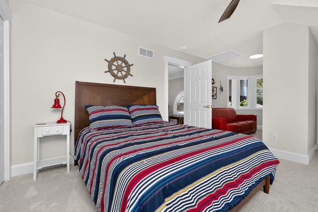 A nautical-themed guest bedroom with a queen bed and an adjoining sitting area